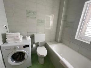a white bathroom with a toilet and a washing machine at Petros Apartments Pag in Pag +66 photos
