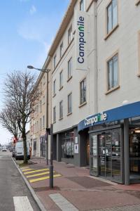 un bâtiment dans une rue de la ville avec un magasin dans l'établissement Campanile Epinal Centre - Gare, à Épinal