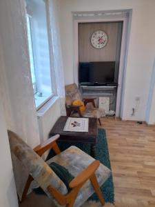 sala de estar con 2 sillas, mesa y reloj en Charming house "Luisi" in green garden Maribor 75m2, en Maribor