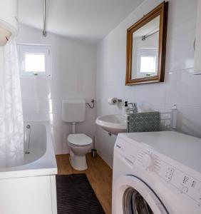 ein weißes Badezimmer mit einem WC-Waschbecken und einer Waschmaschine in der Unterkunft Apartment Vedrana 2142 in Peroj