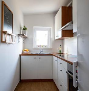 eine weiße Küche mit einem Waschbecken und einem Fenster in der Unterkunft Apartment Vedrana 2142 in Peroj