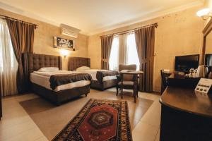 a hotel room with two beds and a television at Royal Stone Houses - Goreme in Göreme