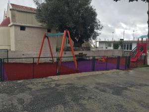a playground with a swing set on a fence at Drosostalida in Áno Sími