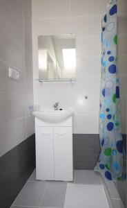 a white bathroom with a sink and a mirror at Apartmány Amália in Piešťany