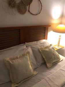 a bed with white pillows and a wooden headboard at Oxe Rooms - Quartos no Centro in Salvador