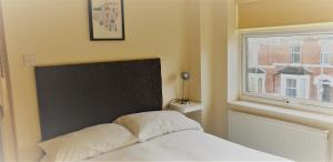 Swindon Old Town Duplex - EnterCloud9SA في سويندون: غرفة نوم بسرير مع نافذة ولحاف ابيض