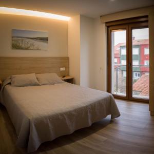 1 dormitorio con cama y ventana grande en Apartamentos turisticos HAZ AMIGO en Muxía