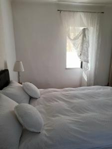 Cama blanca con almohadas en un dormitorio con ventana en Charming house "Luisi" in green garden Maribor 75m2 en Maribor