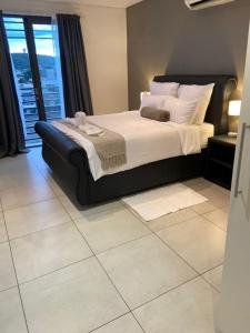 a bedroom with a large bed with a tiled floor at Worm Wood Homes at City Junction in Windhoek