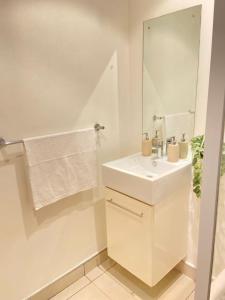 a white bathroom with a sink and a mirror at Worm Wood Homes at City Junction in Windhoek