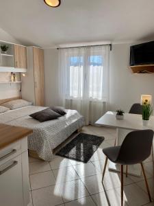 a white bedroom with a bed and a table and a desk at Guest House Renata in Plomin