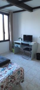 a bedroom with a desk with a computer on it at Chambre indépendante à la campagne in Puycalvel Lautrec