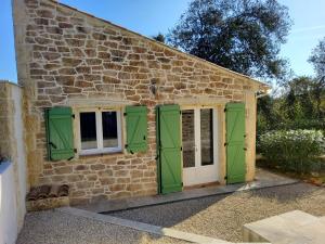a stone cottage with green shutters and a door at Studio Faillant Lorgues spa privatif avec superbe piscine in Lorgues