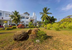 a large white house with some rocks in the grass at Sea Breeze Ambalangoda in Ambalangoda