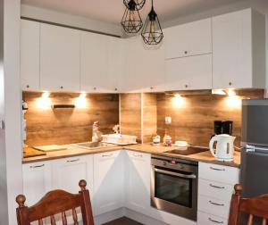 una cucina con armadietti bianchi ed elettrodomestici in acciaio inossidabile di Apartament z basenem a Kościelisko