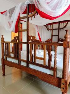 un letto in legno con baldacchino in una stanza di Kome beach Apartment one a Jambiani