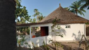 a small white house with a thatched roof at Case traditionnelle diola au bord de l'océan in Cap Skirring
