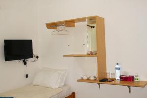 Habitación con cama, TV y estante. en Seginy Seaview en Guraidhoo