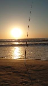 una canna da pesca sulla spiaggia con l'oceano di Case traditionnelle diola au bord de l'océan a Cap Skirring