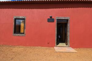 een rood gebouw met een deur en twee ramen bij QUINTA DO FALCÃO in Almagreira