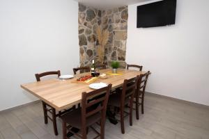 a wooden dining room table with chairs and a television at Apartment Maya Bellissima in Tugare