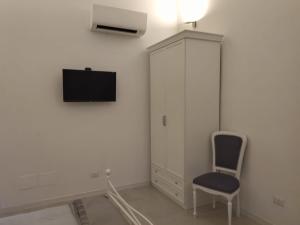 um quarto branco com uma cadeira e uma televisão na parede em Casa Vacanze Laura1 em Lecce