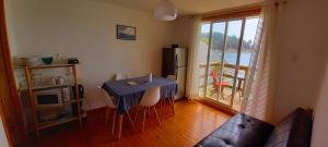 a living room with a table with chairs and a window at Cabaña Coliumo Tomé in Dichato