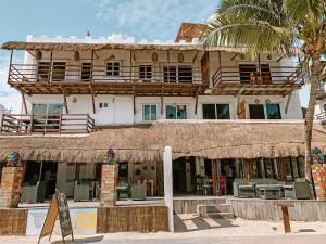 a building on the beach with a straw roof at El Fuerte Beach Resort in Mahahual