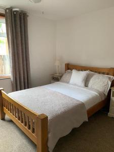 a bedroom with a large bed with white sheets and a window at Mary's Apartment in Rothes