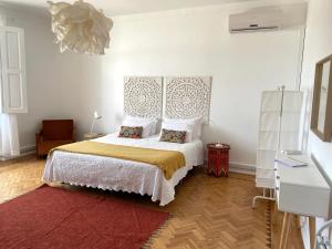 a bedroom with a bed with a headboard and a red rug at Formosa Guest House in Tavira