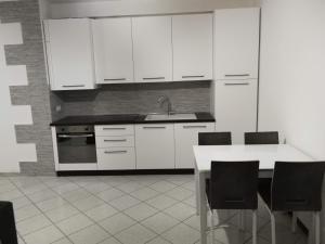 - une cuisine avec des placards blancs, une table et des chaises dans l'établissement Green Relax in Maccagno, à Maccagno Inferiore