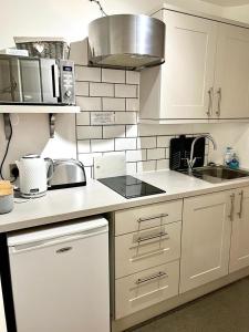 a small kitchen with white cabinets and a sink at The Paddock at Peacock Farm near Belvoir Castle in Redmile