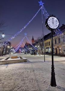 a clock on a pole in a square with christmas lights at Sofia Loft in Bistriţa