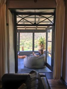 
a woman sitting on a bed in front of a window at The Old School House in Calitzdorp
