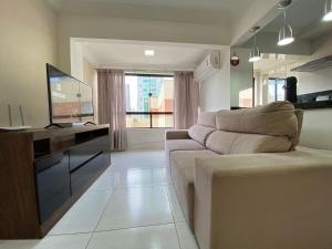 een woonkamer met een bank en een televisie bij BK54 - Climatizado, TV Smart, Conforto, Garagem in Balneário Camboriú