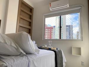 een slaapkamer met een wit bed en een raam bij BK54 - Climatizado, TV Smart, Conforto, Garagem in Balneário Camboriú