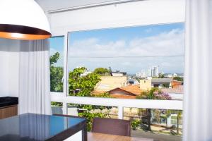 a room with a large window with a table and a view at Apto. 3 dorm. entre Praia da Cal e Lagoa Violão in Torres