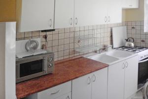 a kitchen with white cabinets and a sink and a microwave at holiday home, Kolczewo in Kołczewo