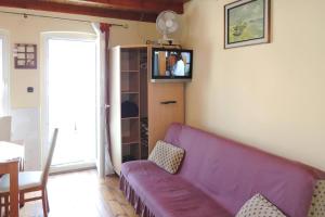 a living room with a purple couch and a tv at Holiday flat, Miedzyzdroje in Międzyzdroje