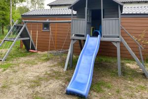 a playground with a blue slide next to a house at Bungalows, Dziwnow in Dziwnów