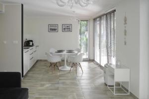 a white dining room with a table and white chairs at Apartment, Lukecin in Łukęcin