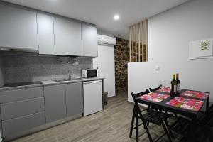 eine Küche mit weißen Schränken und einem Tisch mit Stühlen in der Unterkunft O Visconde - Alojamento local in Lamego