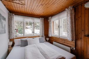 a bedroom with a bed and two windows at Chaloupka na stráni in Ostravice