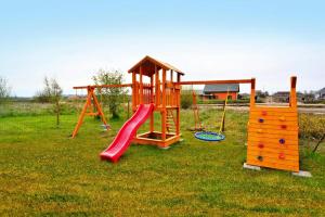 a playground with a slide and playset in the grass at Apartments, Sarbinowo in Sarbinowo