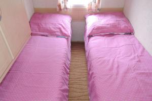 two beds in a small room with pink sheets at Bungalow, Mrzezyno in Mrzeżyno