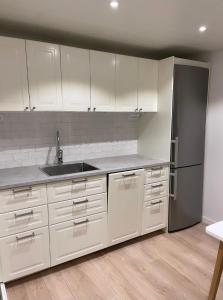 a kitchen with white cabinets and a sink and a refrigerator at Backes Lillstuga in Borlänge