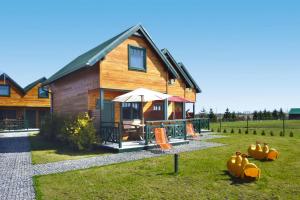 a wooden house with an umbrella in the grass at Terraced Houses, Sarbinowo in Sarbinowo