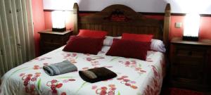 Un dormitorio con una cama con almohadas rojas. en La Hijuela, en Navafría