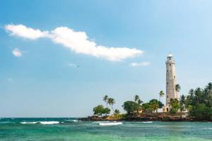 un phare sur une île dans l'océan à côté de l'eau dans l'établissement The Ocean Villa, à Matara
