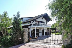 une maison blanche avec une clôture noire et un portail dans l'établissement holiday home, Stepnica, à Stepnica